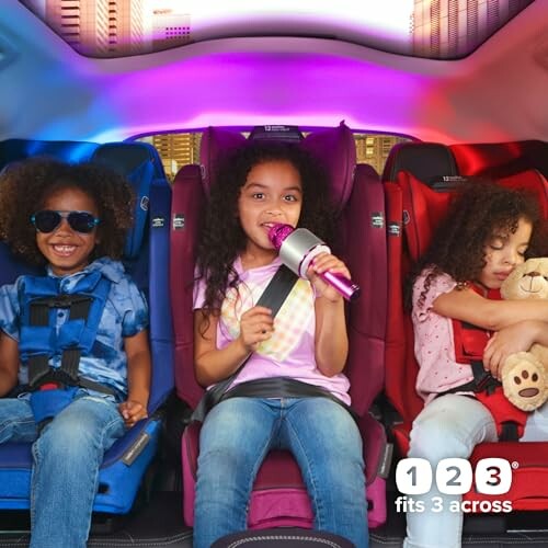 Three children in car seats, one holding a microphone, another with a teddy bear.