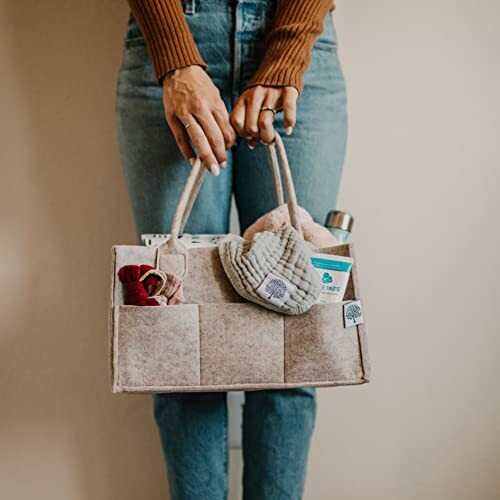 Person holding a felt bag organizer with various items.