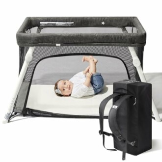 Baby lying in a portable playpen with a carry bag nearby.